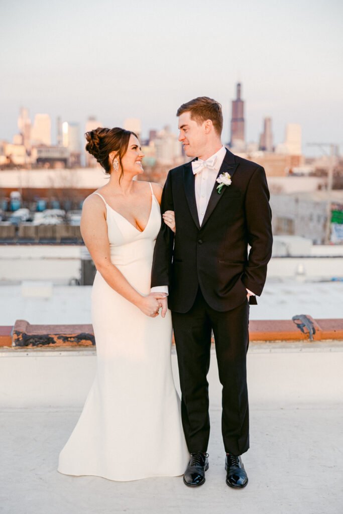 A couple stares into each others eyes. The Chicago skyline is in the background as the sun sets.